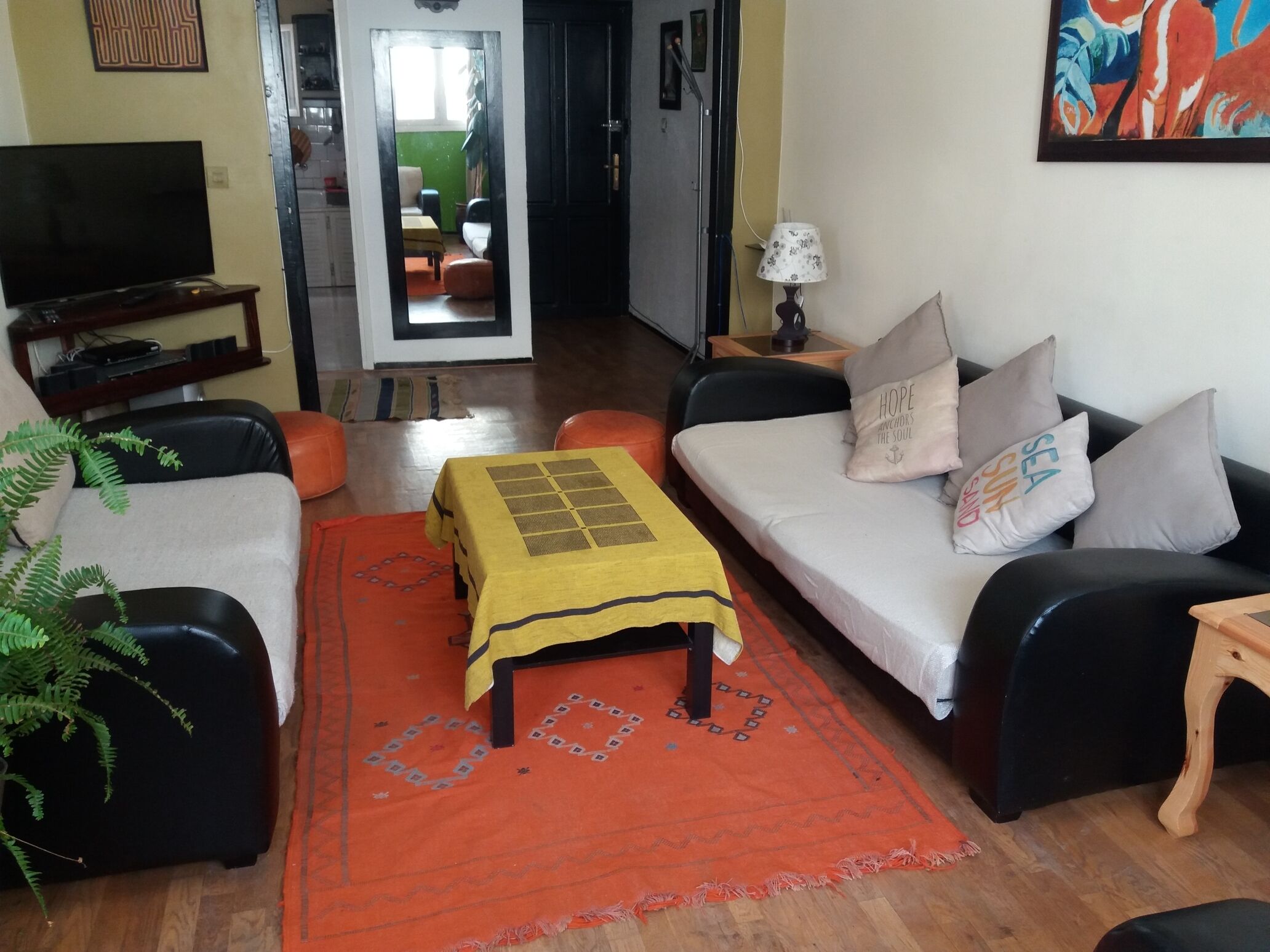 Ein Wohnzimmer mit einer Couch, einem Couchtisch, einem Fernseher und einer Pflanze.