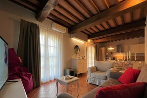 A cozy living room with a fireplace, a dining area, and a kitchen. - Borgo del Silenzio - Ginepro two-bedroom apartment with private terrace (Provincia di Pisa)