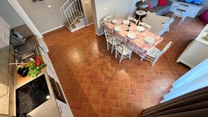 A dining area with a table set for four, a kitchen with a stove and sink, and a living area with a sofa and TV.