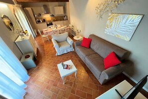A living area with a sofa, a coffee table, and a dining table set for four. - Borgo del Silenzio - Ginepro two-bedroom apartment with private terrace (Provincia di Pisa)
