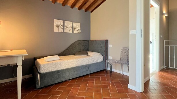 A small, cozy bedroom with a single bed, a chair, and a table.