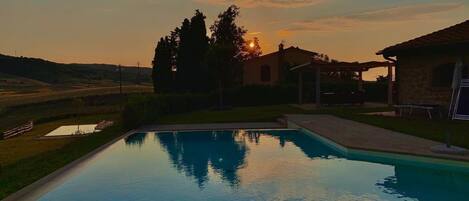 Una piscina rectangular con vistas claras del paisaje circundante, que incluye una casa y árboles.
