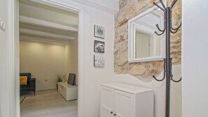 A hallway with a white cabinet, a coat rack, and a stone wall. - Holiday house Filip * large plot with garden, private pool, free WiFi (Nedescina)