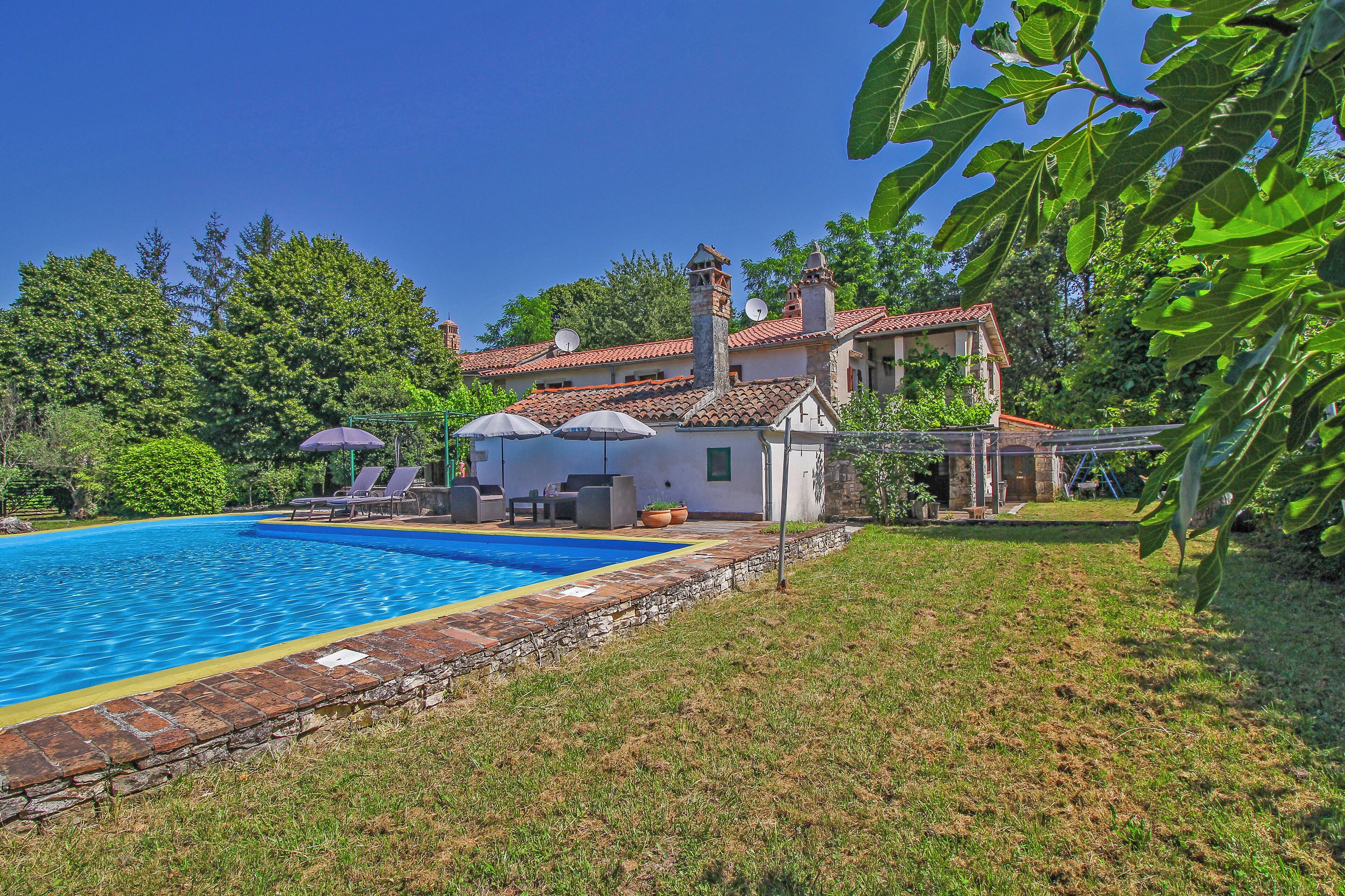 A villa with a swimming pool, outdoor seating, and a garden.