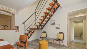 A staircase with wooden steps and black railings, a dining area with a wooden table and chairs, and a small ottoman. - Holiday house Filip * large plot with garden, private pool, free WiFi (Nedescina)