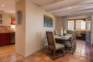 A dining area with a wooden table, chairs, and a painting on the wall.