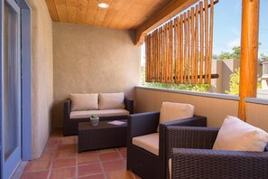 A covered outdoor seating area with wicker furniture and a cushioned bench.