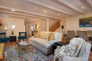 A spacious living area with a sofa, chairs, a coffee table, and a staircase.