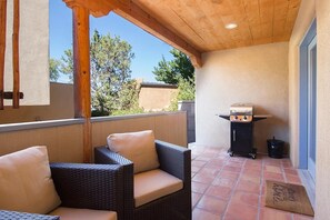 A covered patio with wicker furniture and a grill.