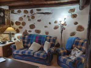 Een gezellige woonkamer met een stenen muur, twee geruite banken, een lamp en een vloerlamp.
