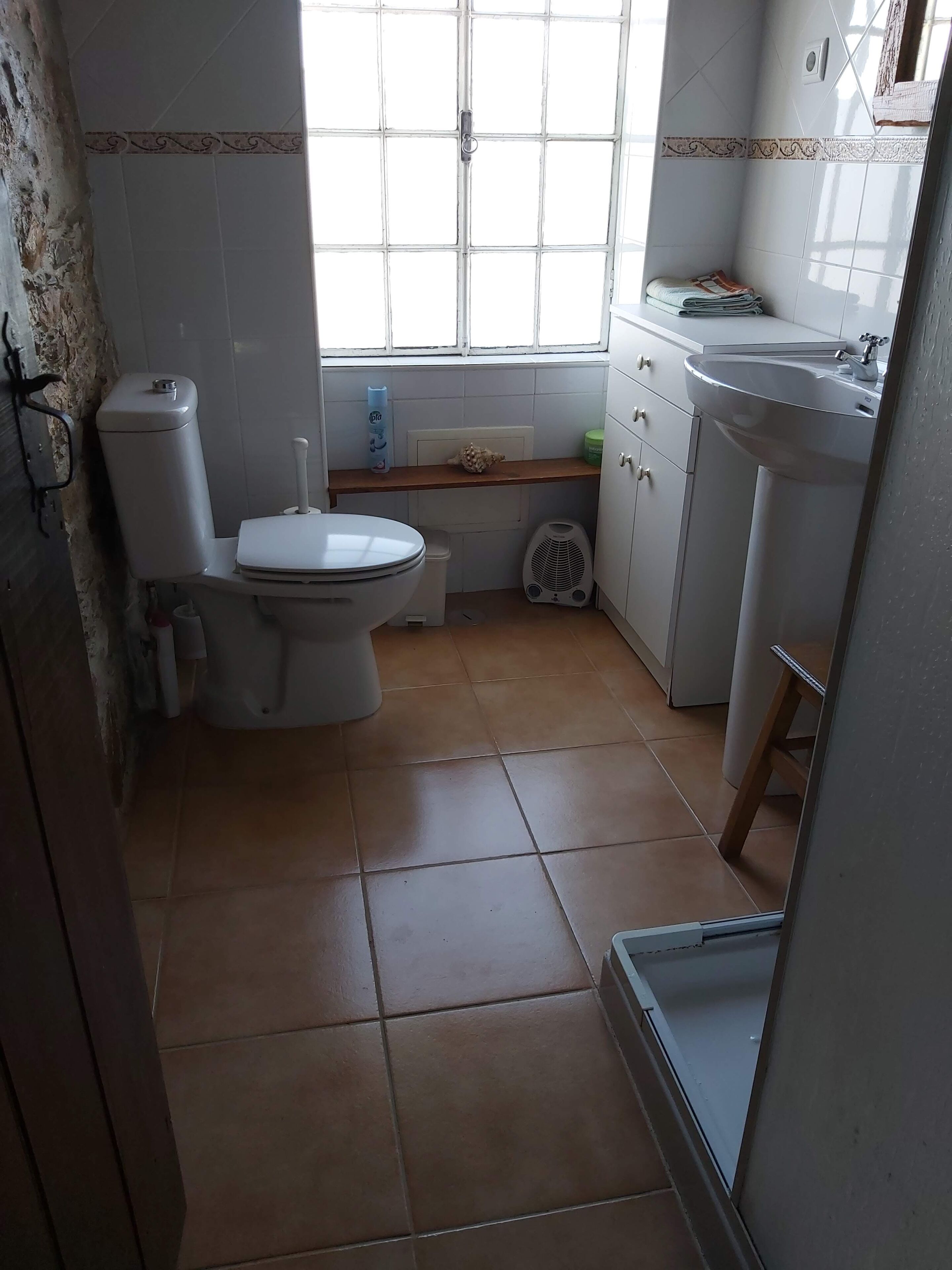 Ein kleines, sauberes Badezimmer mit Toilette, Waschbecken und Fenster.
