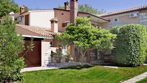 Ein zweigeschossiges Haus mit einem Ziegeldach, einem Backstein-Schornstein und einem gepflegten Garten mit verschiedenen Pflanzen und einem Rasen.