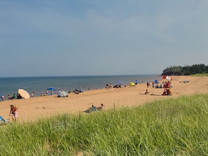Ein Strand mit Personen, Sonnenschirmen und Liegestühlen.