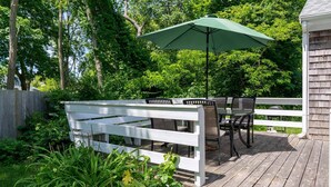 A wooden deck with a white railing, a table with chairs, and a green umbrella. - Walk To Beaches, Main Street, and Harbor. 1BR Cottage. Quiet Area. Captain Gosnold Village 18A (Hyannis)