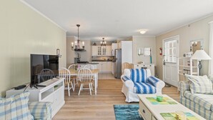 A compact living space with a dining area, a sofa, a TV, and a kitchen in the background. - Walk To Beaches, Main Street, and Harbor. 1BR Cottage. Quiet Area. Captain Gosnold Village 18A (Hyannis)