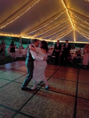 Guests gather under a romantic tent with string lights, surrounded by tables for a memorable celebration.