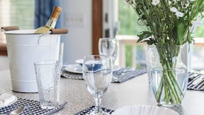 Une table à manger dressée avec des verres, des assiettes et un vase rempli de fleurs.