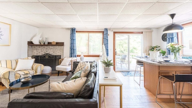 Un salon avec une cheminée, un canapé, une table basse et un coin repas avec un comptoir de cuisine.