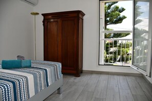 Une chambre à coucher avec un lit, une armoire en bois et une fenêtre donnant sur un paysage verdoyant.