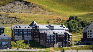 Un grand hôtel à plusieurs étages, doté d’une façade en pierre et de nombreux balcons, situé sur une colline et offrant une vue sur le paysage environnant.