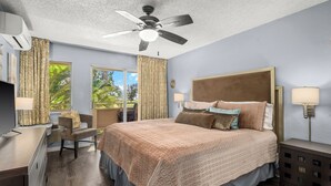 A hotel room with a bed, a desk, a chair, a ceiling fan, and a window with curtains.