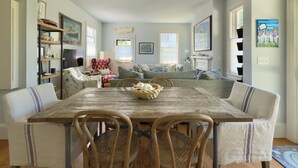 A dining room with a wooden table, chairs, and a central woven basket. - Stylish In-Town Cottage- Walk to everything! (Vineyard Haven)