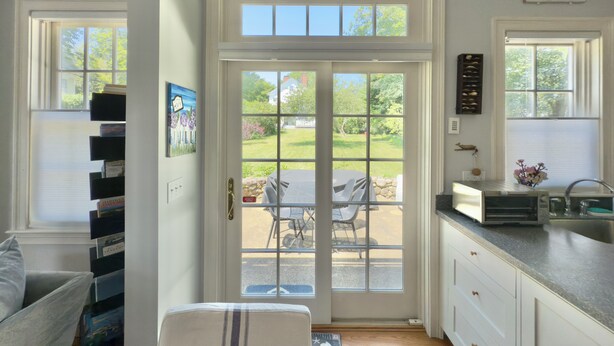 A kitchen with a view of a patio, a dining area, and a bookshelf. - Stylish In-Town Cottage- Walk to everything! (Vineyard Haven)