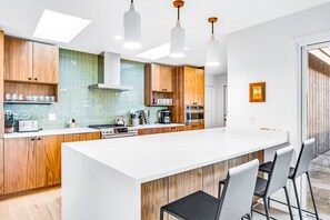 Eine moderne Küche mit Holzschränken, einer weißen Kochinsel und Edelstahlgeräten.