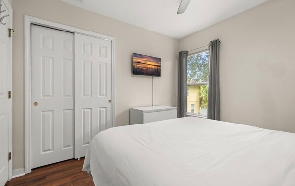 A bedroom with a bed, a white door, a radiator, and a window with curtains.