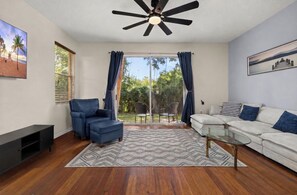A living room with a ceiling fan, a sofa, a coffee table, and a TV stand.