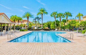 A swimming pool with lounge chairs and palm trees.