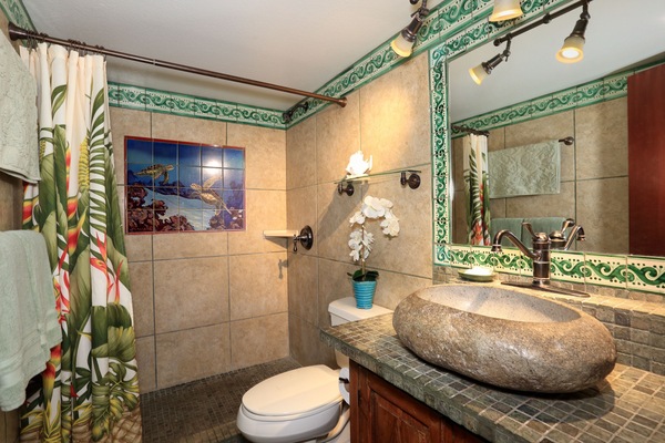 Remodeled bathroom with rock-shaped sink and turtle wall mural in shower.