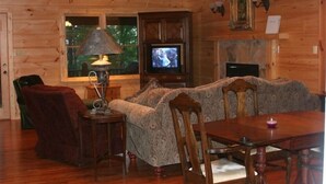 A cozy log cabin interior with a sofa, dining table, chairs, a television, and a fireplace. - Townsend, Tn & Smoky Mountains! Wooded Privacy & Sleeps 15 (Townsend)
