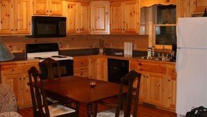 A wooden cabin-style kitchen with a dining table and chairs, a microwave, stove, and refrigerator. - Townsend, Tn & Smoky Mountains! Wooded Privacy & Sleeps 15 (Townsend)
