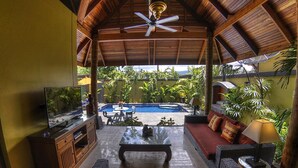 A covered outdoor seating area with a pool, wooden furniture, and a television. - Private Villa with Swimming pool, jetted Plunge Pool and Free Transfers (Koh Samui)