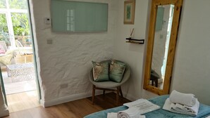 Une chambre à coucher avec un lit, une chaise, un miroir et une vue sur l’extérieur.