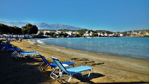A beach with rows of blue lounge chairs and a clear view of the sea and distant mountains. - Heliopetra Studios, near beaches (chania)