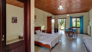 A bedroom with a wooden ceiling, a bed with white linens, a wooden wardrobe, and a dining table with chairs. - Heliopetra Studios, near beaches (chania)