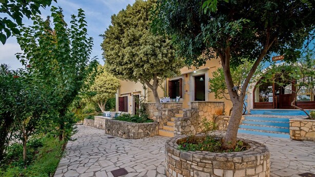 A courtyard with stone pathways, a tree planter, and a building with a sign that reads "RECEPTION". - Heliopetra Studios, near beaches (chania)
