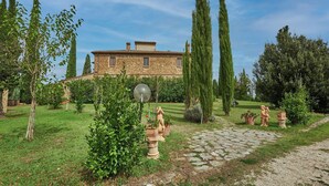 A stone building with a garden pathway leading to it, surrounded by trees and potted plants. - Apartment on the first floor with a beautiful panoramic view, Air conditioning. (Torrita di Siena)