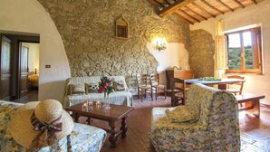 A rustic interior with stone walls, wooden furniture, and a dining area. - Apartment on the first floor with a beautiful panoramic view, Air conditioning. (Torrita di Siena)