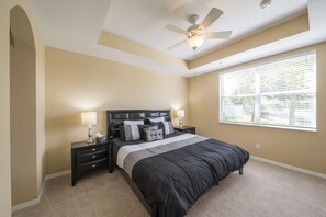 A bedroom with a bed, nightstands, a ceiling fan, and a window with blinds.