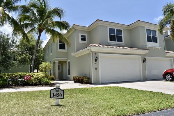 A two-story house with a garage, a well-maintained lawn, and a street sign indicating the address 1450.