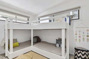 Ein Schlafraum mit Etagenbetten, einem Fenster, einer hängenden Dekoration und einem Teppich.