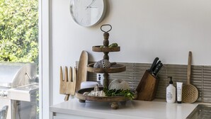 Un comptoir de cuisine avec un présentoir en bois à trois niveaux, une horloge et divers ustensiles de cuisine.