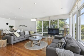 Ein modernes Wohnzimmer mit einem grauen Sofa, einem Couchtisch und einem Fernseher auf einem Lowboard.