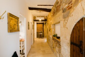 A hallway with a stone wall, wooden door, and a small table with a vase.