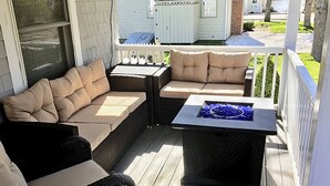 Ein überdachter Balkon mit Korbmöbeln und einem Feuerbereich.