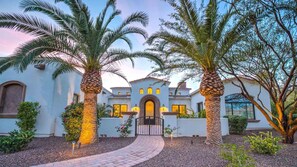 Stately residence with a central entrance, arched doorway, and beautifully maintained garden.