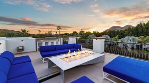 Relax by the fire pit surrounded by comfortable seating and breathtaking views of the surrounding mountains and lush greenery.